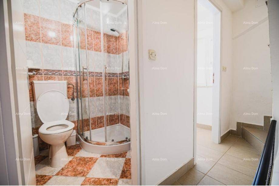 Badezimmer mit Toilette und Eckdusche, ausgestattet mit gemusterten Fliesen.
