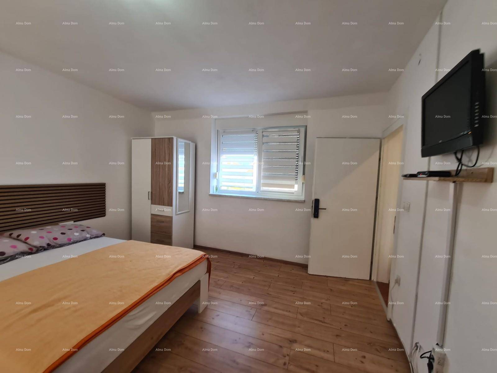 Schlafzimmer mit Doppelbett, Kleiderschrank und Fernseher an der Wand, mit Holzboden.