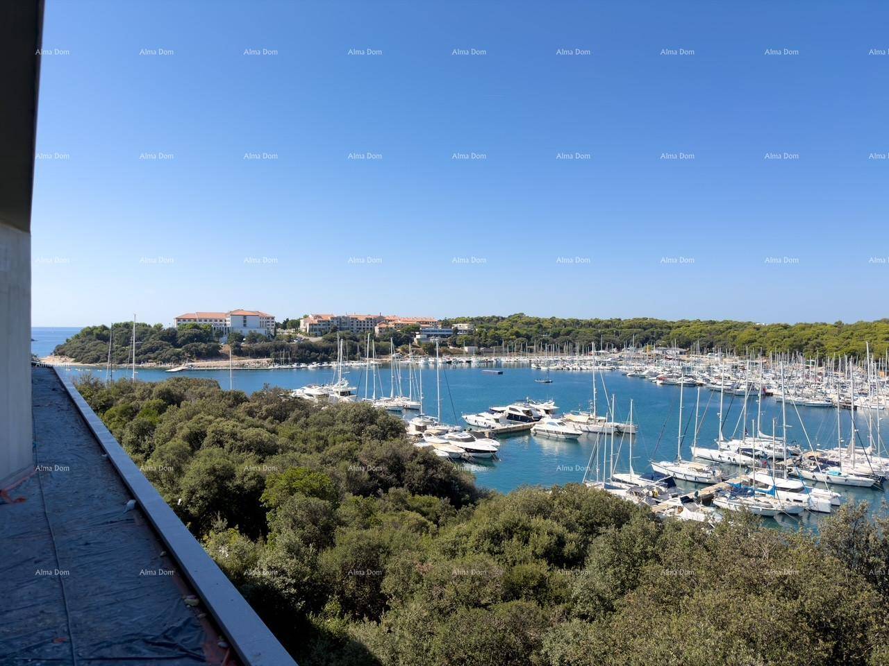 Geräumiger Balkon im Rohbau mit Panoramablick auf den Yachthafen, das Meer und die bewaldete Küste.