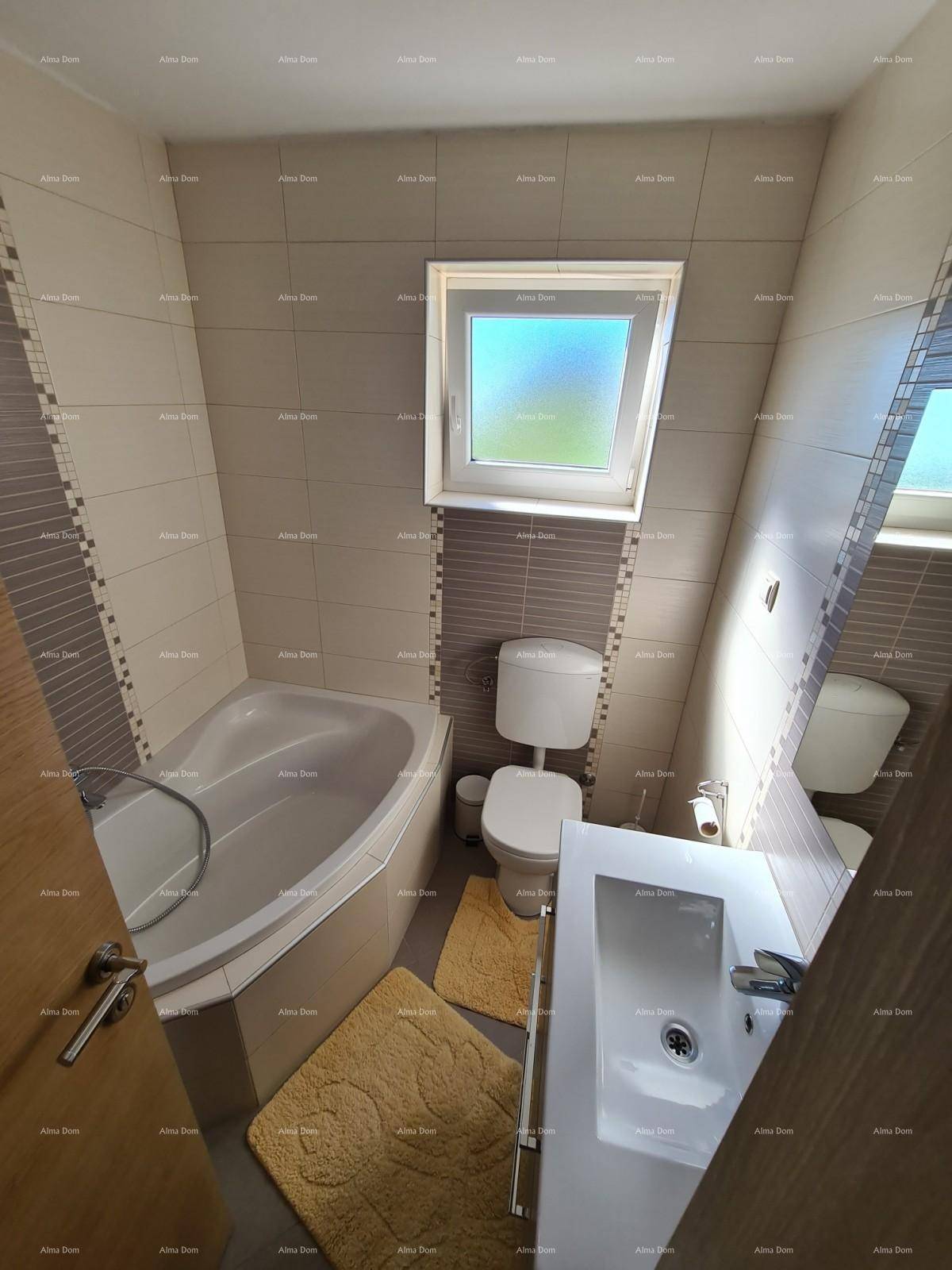 Helles Badezimmer mit Eckbadewanne, WC, Waschbecken und Fenster, freundlich gefliest.