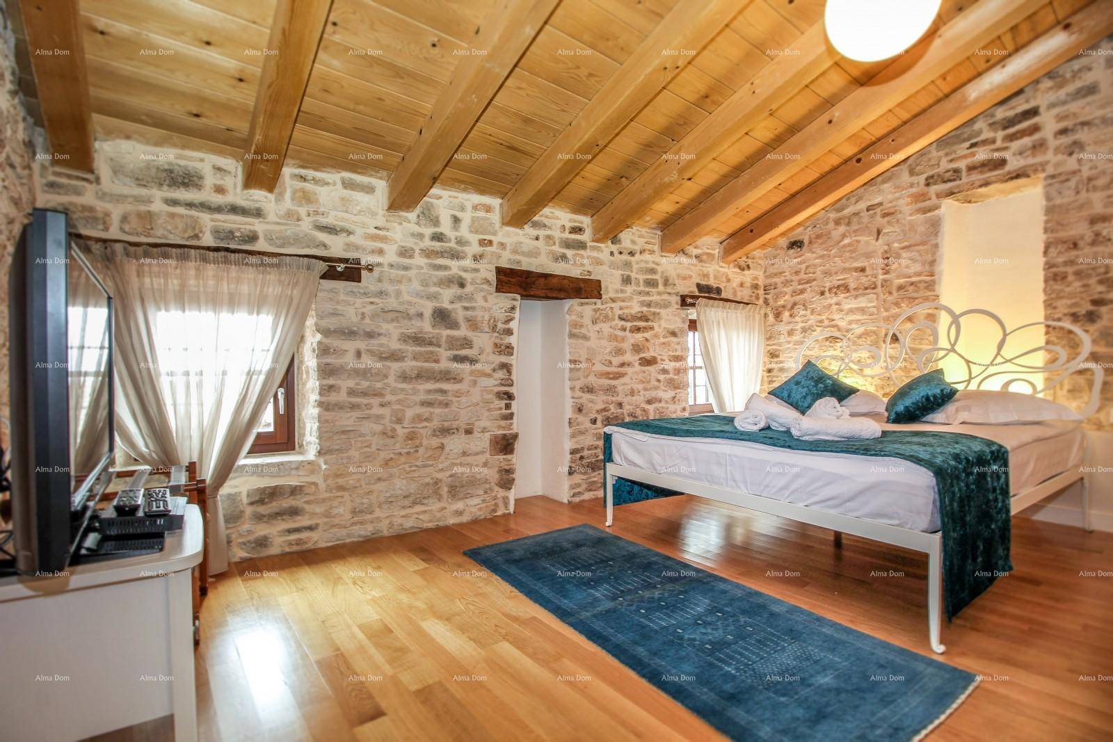 Rustikales Schlafzimmer mit Holzbalkendecke, freigelegten Steinwänden und Holzboden.