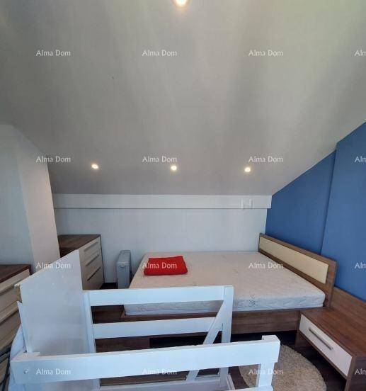 Schlafzimmer im Dachgeschoss mit Einzelbett, Nachttischen und blauer Akzentwand, unter schräger Decke.