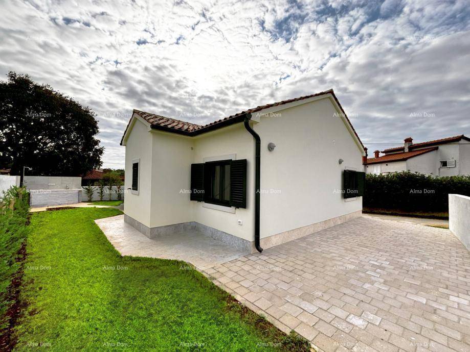 Seitenansicht des Hauses mit gepflasterter Auffahrt, grünen Fensterläden und Rasenfläche.