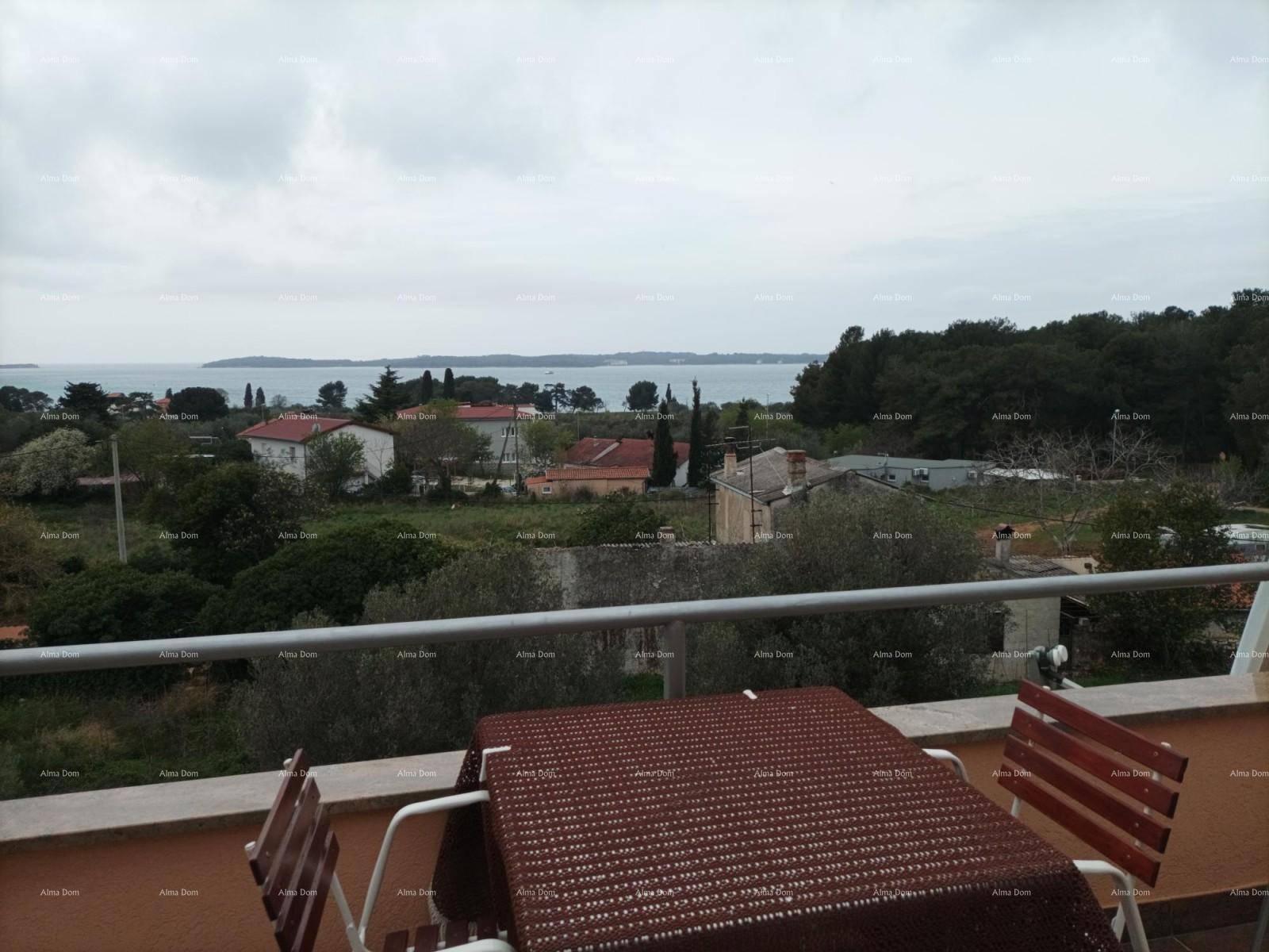 Terrasse mit Esstisch und Stühlen, bietet einen weiten Blick auf das Meer und die Küste.