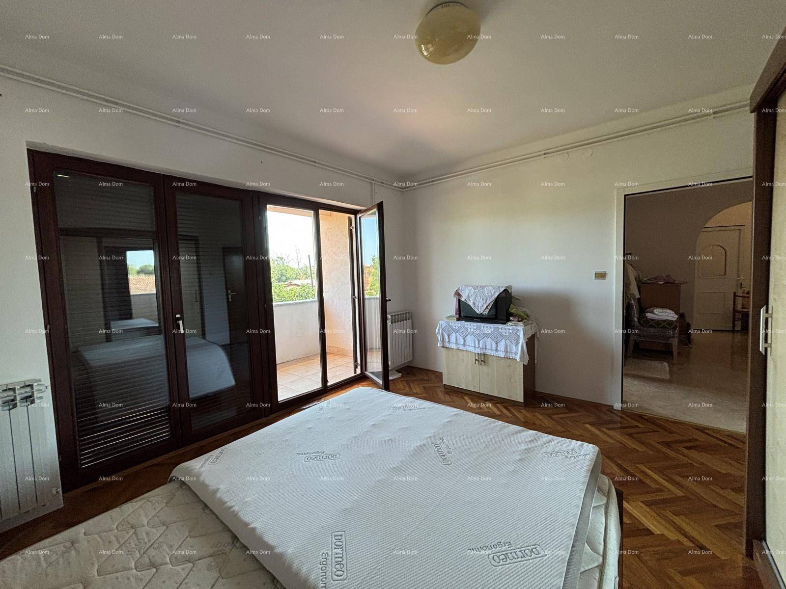 Schlafzimmer mit Parkettboden, Bett und Balkontür, die viel Tageslicht hereinlässt.