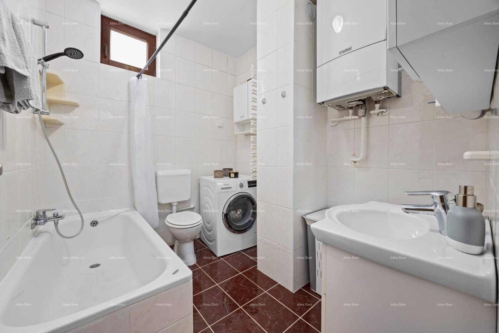 Badezimmer mit Badewanne, Toilette, Waschmaschine und Fenster, funktional und gefliest.