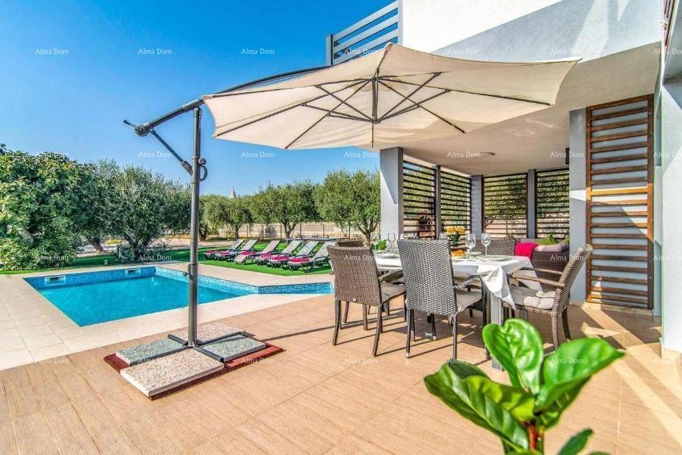 Sonniger Essbereich im Freien unter einem großen Sonnenschirm, mit Blick auf den Pool und Garten.