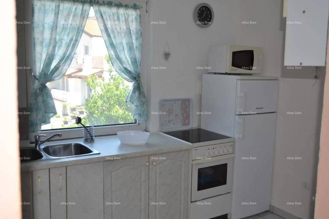 Kleine Küche mit Fenster, Spüle, Herd und Kühlschrank, funktional eingerichtet.