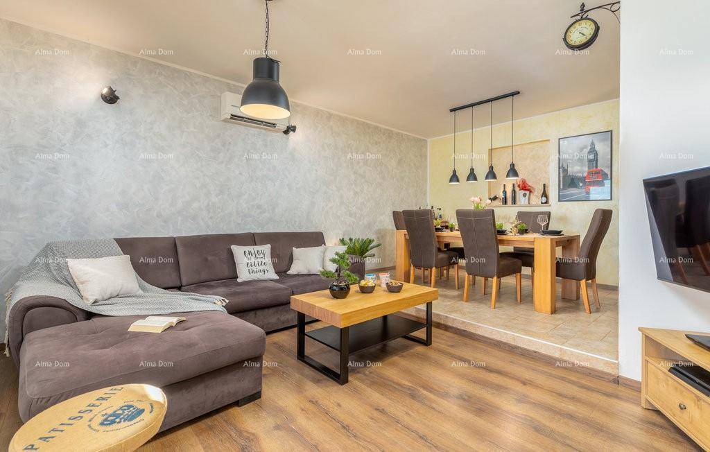 Gemütlicher Wohnbereich mit großem Sofa, Couchtisch und Essbereich im Hintergrund, verbunden durch eine Stufe.