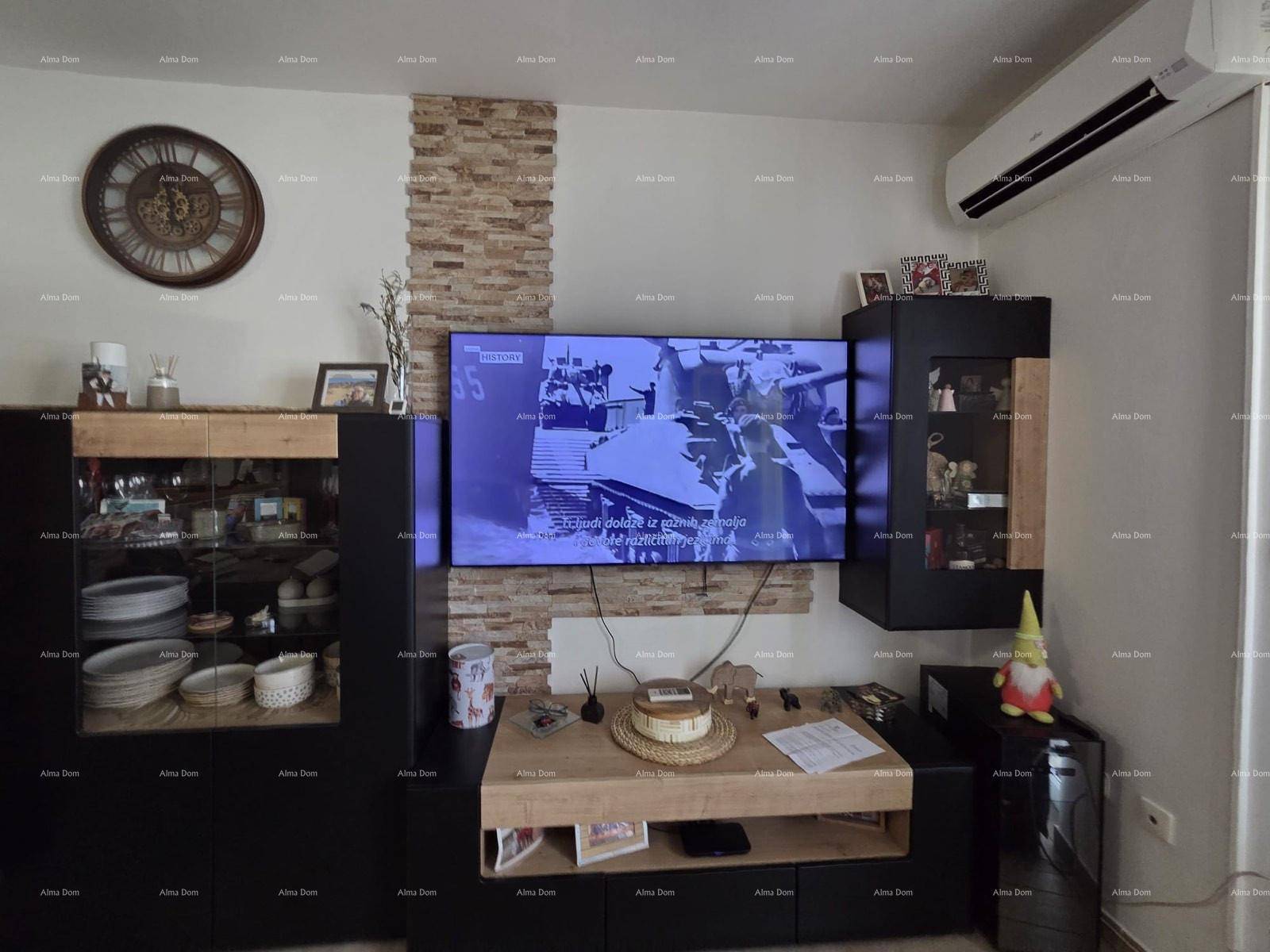 Wohnzimmer mit großem Flachbildfernseher, Steinwandakzent und modernen Möbeln.