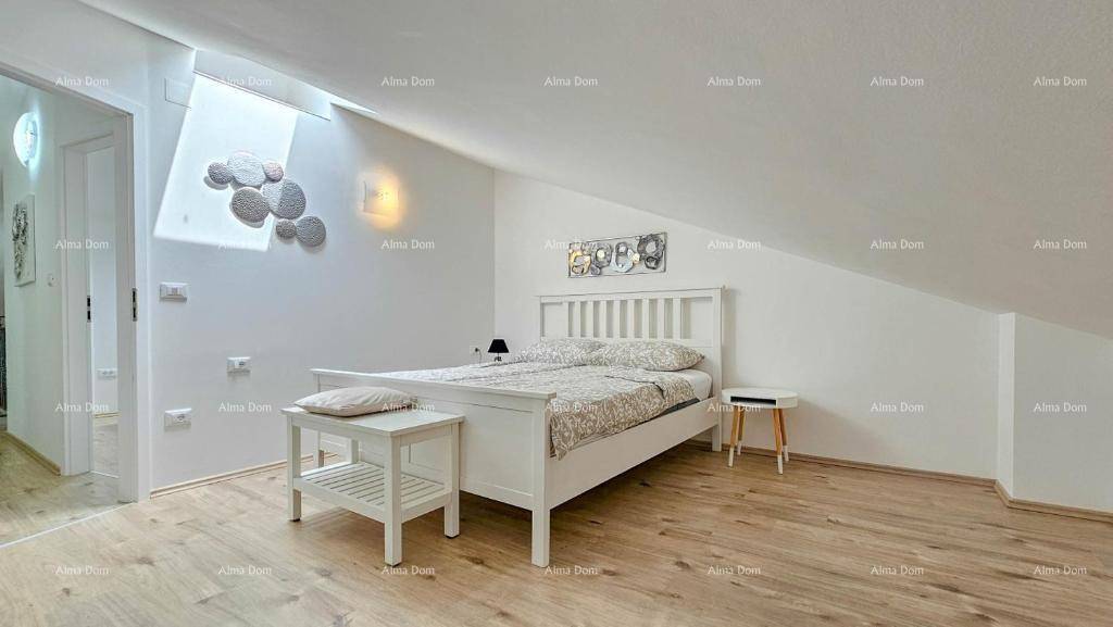 Helles Schlafzimmer im Dachgeschoss mit Holzboden, weißem Bett und schrägen Wänden.
