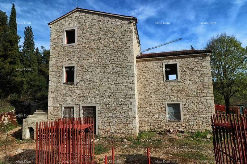 Steinhaus im Rohbauzustand mit traditioneller Architektur und umliegender Natur.