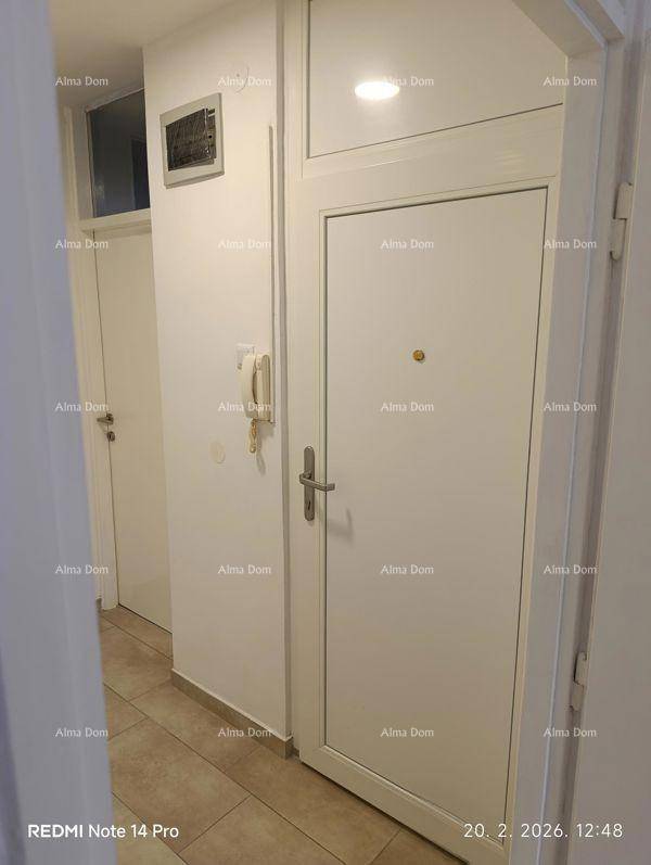 Eingangsbereich mit weißer Wohnungstür, Gegensprechanlage und praktischem Fliesenboden.