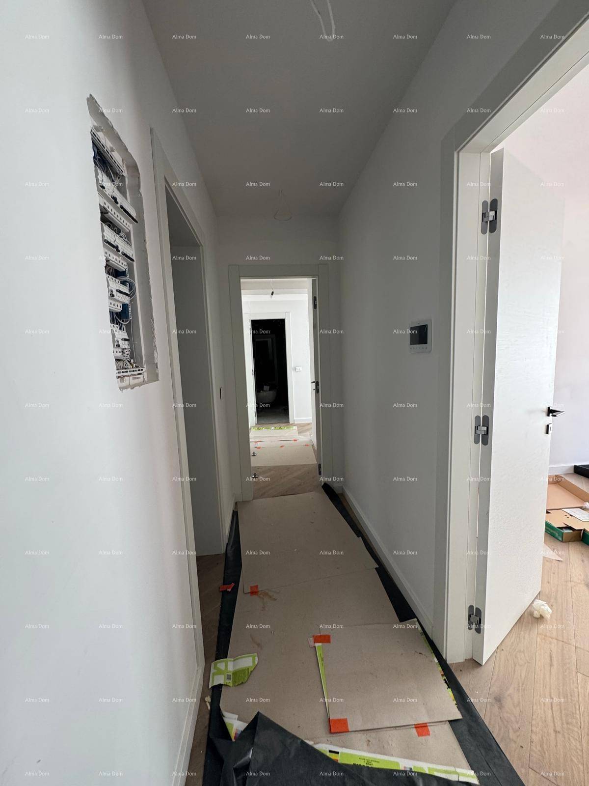 Langer Flur in einem Neubau mit Holzboden und sichtbaren Elektroinstallationen.