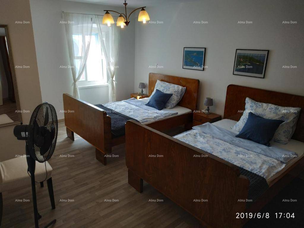Schlafzimmer mit zwei Einzelbetten, Fenster und einem Ventilator für zusätzliche Kühlung.