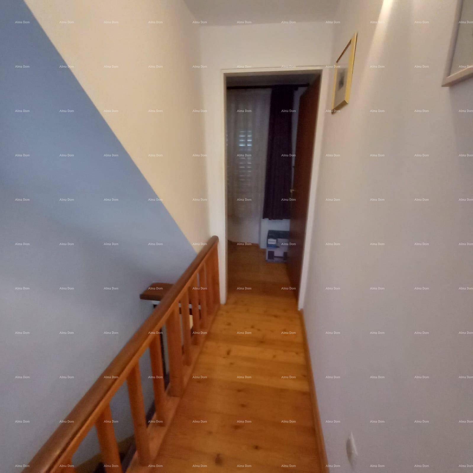 Flur mit Holzgeländer und Holzboden, der zu einem weiteren Raum führt.