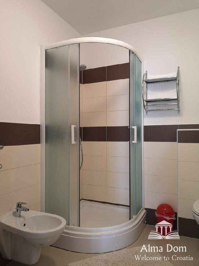 Modernes Badezimmer mit Duschkabine, Bidet und zweifarbigen Fliesen an den Wänden.