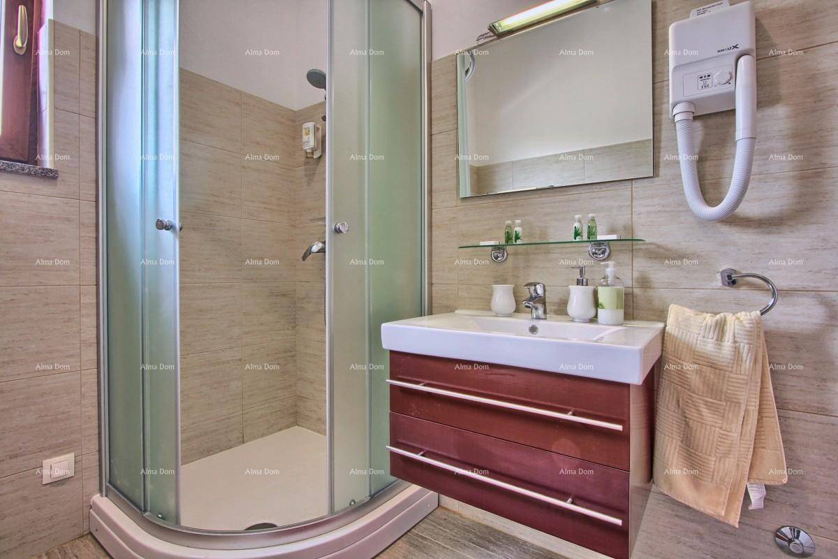 Modernes Badezimmer mit beigen Fliesen, Duschkabine und Einzelwaschbecken.
