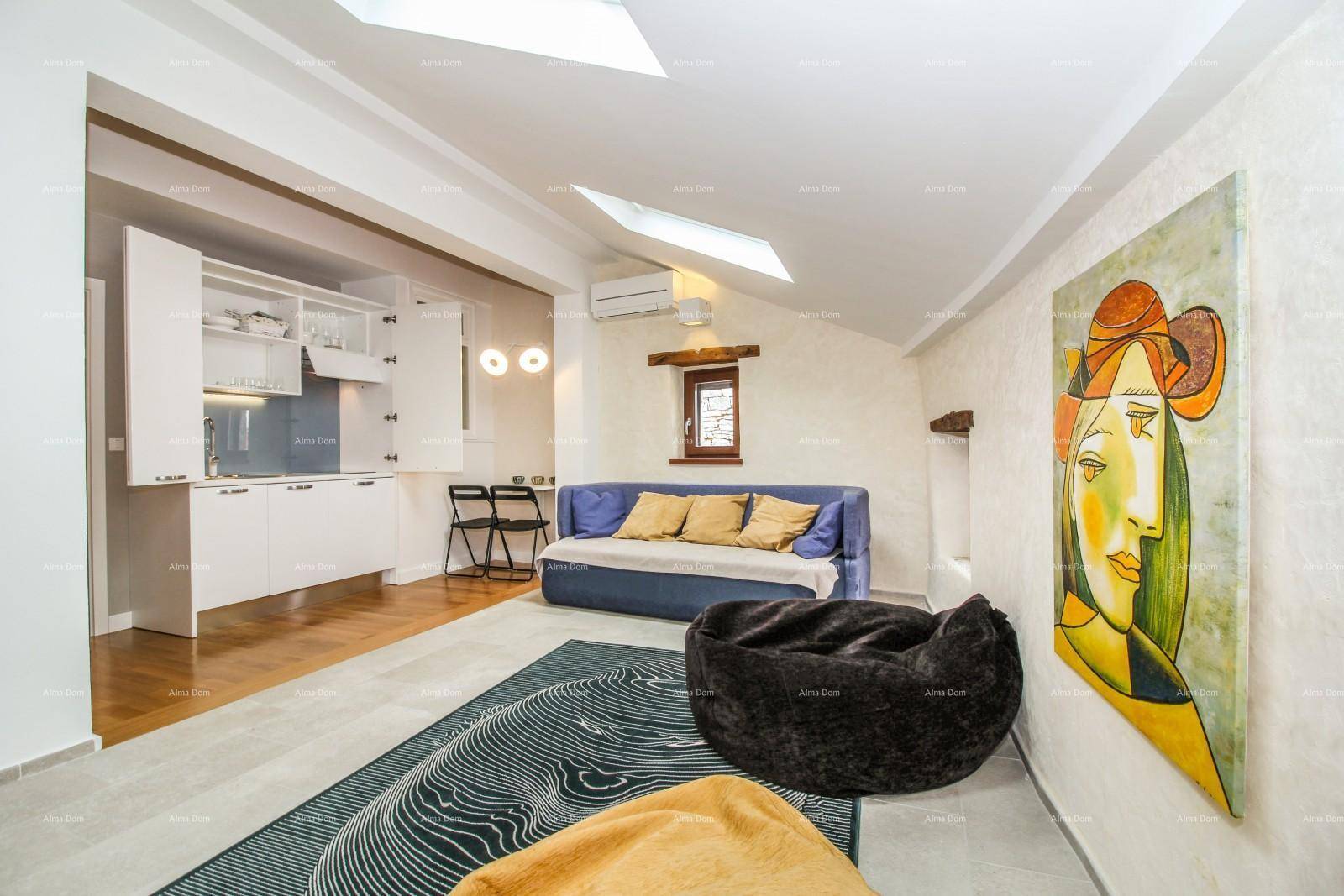Helles Dachgeschoss-Wohnzimmer mit Küchenzeile, Sofa und moderner Kunst an der Wand.