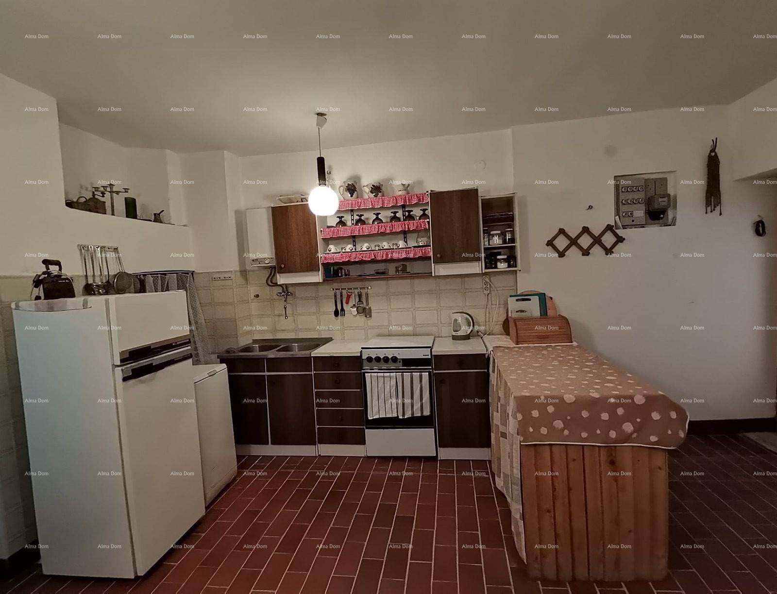 Traditionelle Küche mit Einbauschränken, Herd und Kühlschrank auf Terrakottaboden.