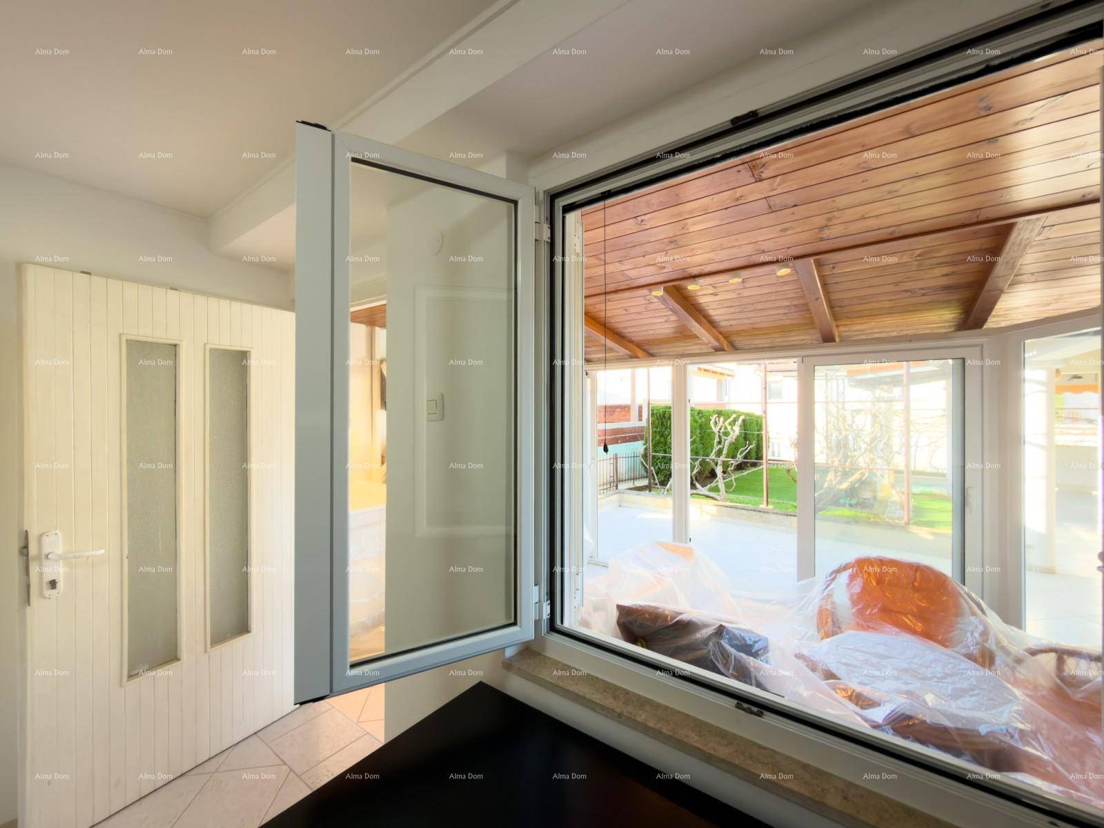 Fensterblick von einem Innenraum in den hellen Wintergarten und den grünen Außenbereich.