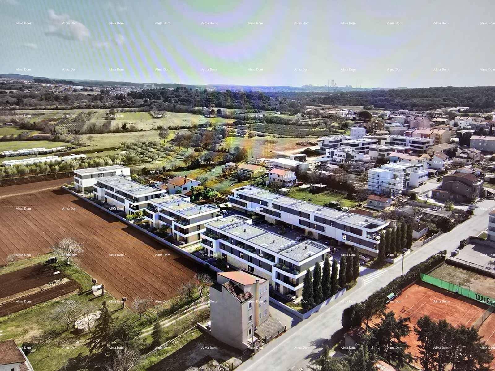 Luftaufnahme eines modernen Wohnkomplexes in ländlicher Umgebung mit Feldern und Häusern.