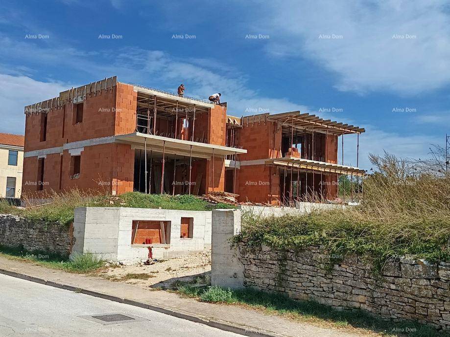 Gebäude im Rohbau mit Ziegelwänden und Betondecken, umgeben von Gerüstkonstruktionen.