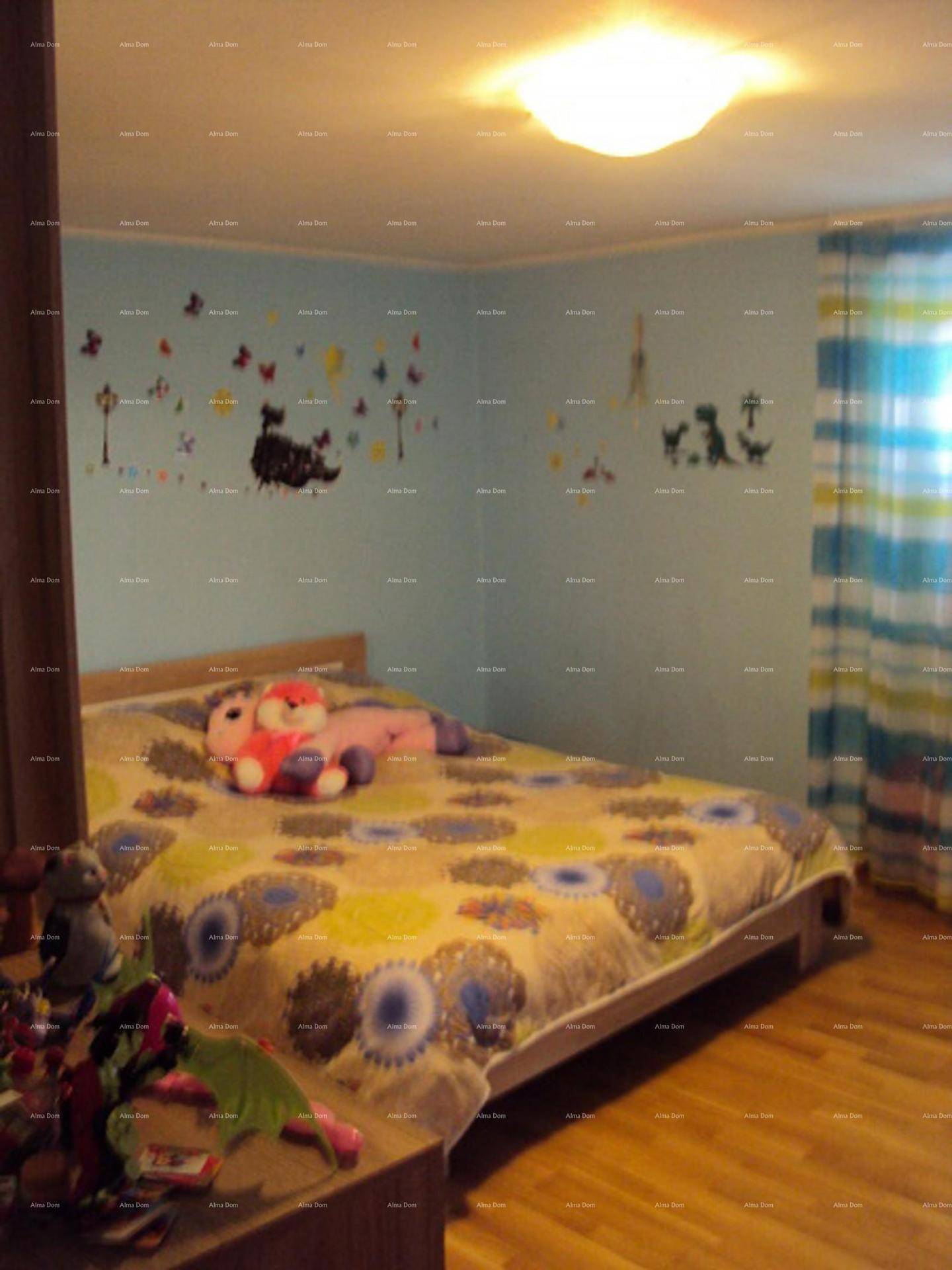 Kinderzimmer mit Bett, farbenfroher Bettdecke und Wanddekorationen.
