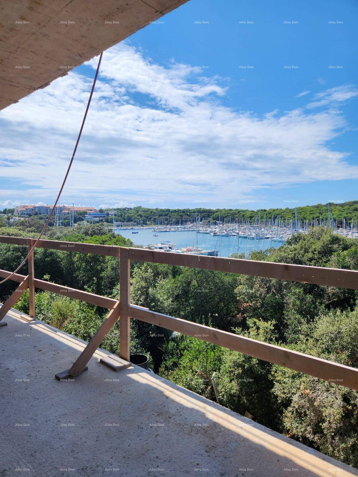 Panoramablick von einem unfertigen Balkon auf den Yachthafen, umgeben von üppiger grüner Vegetation.
