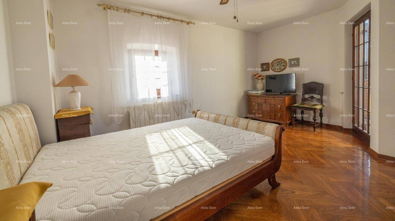 Helles Schlafzimmer mit Parkettboden, Fenster und Zugang zu einem Balkon oder einer Terrasse.