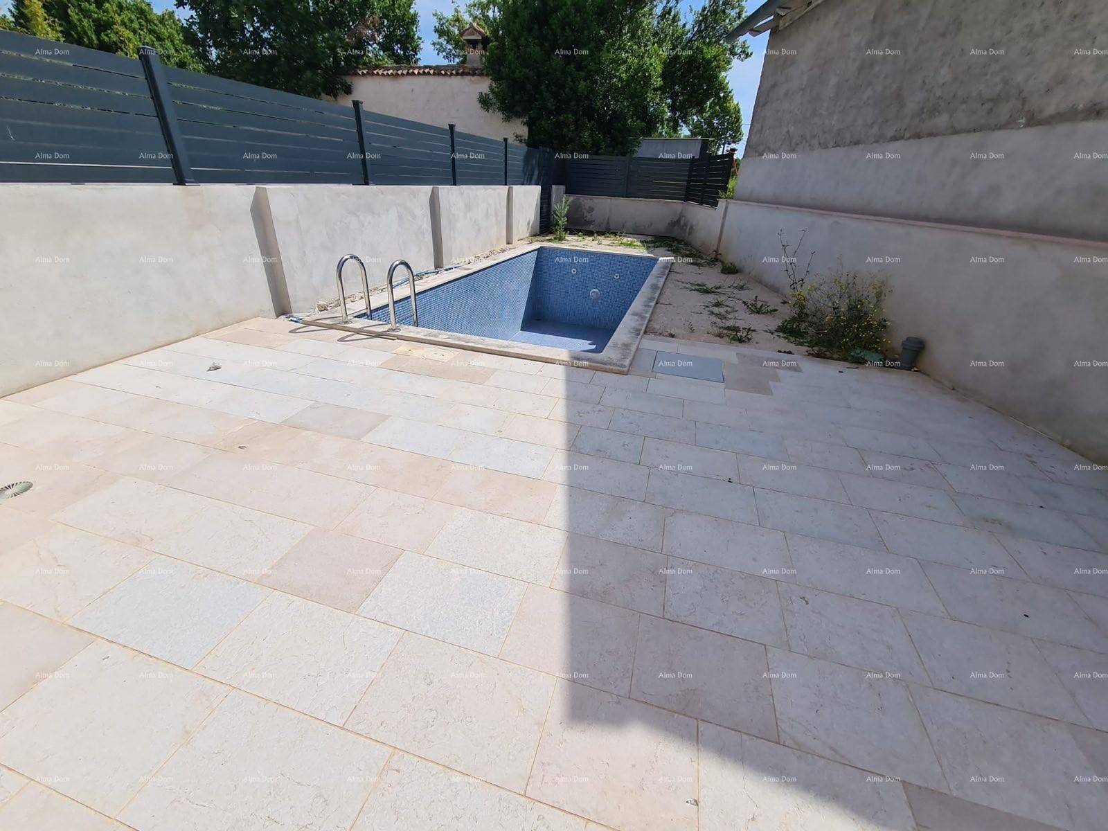 Gepflasterter Außenbereich mit einem kleinen eingelassenen Pool und Zaun.