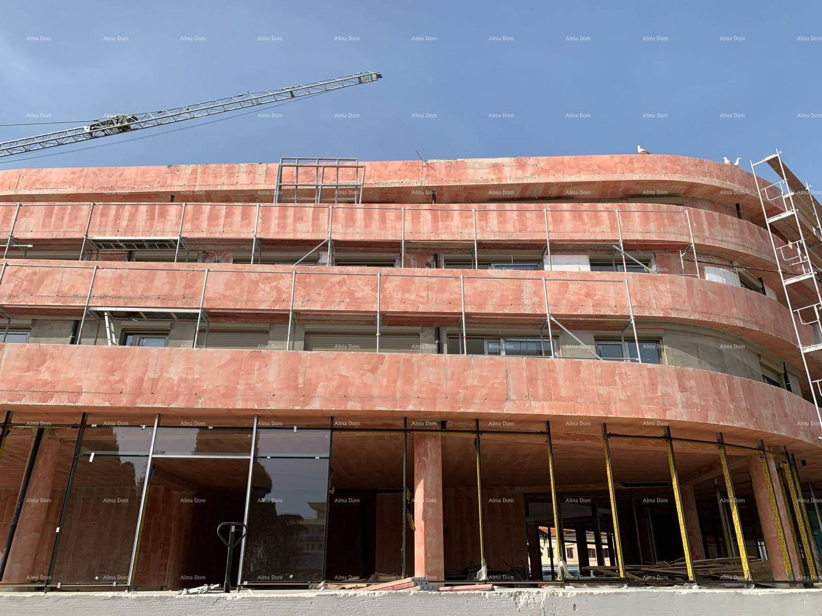 Nahaufnahme der Erdgeschossfassade im Bau mit großen Fensteröffnungen und Betonstruktur.