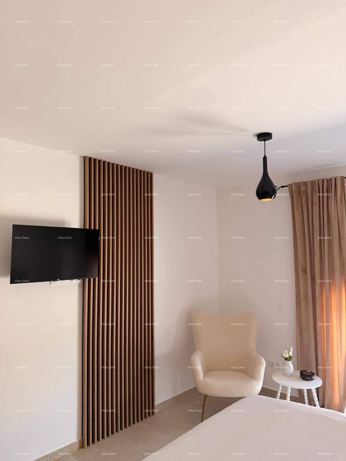 Schlafzimmer mit Sessel, Wandfernseher und dekorativer Holzlamellenwand.