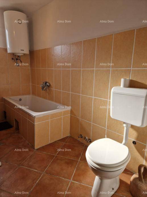 Badezimmer mit beigefarbenen Fliesen, einer Badewanne und einer Toilette.