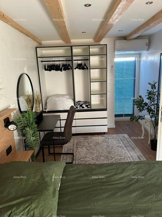 Helles Schlafzimmer mit Holzbalken, offenem Kleiderschrank und Schreibtisch.