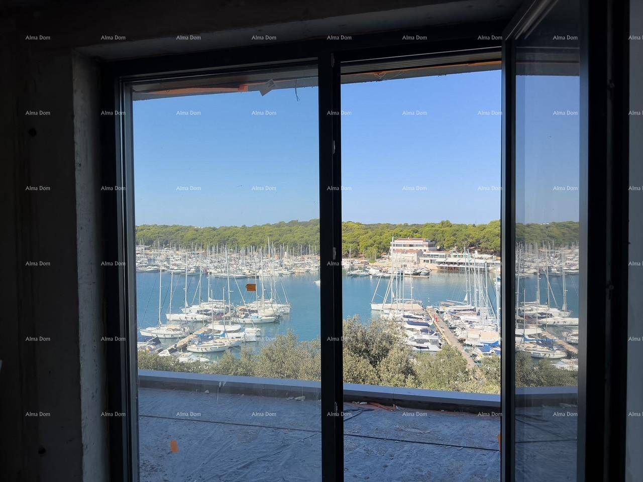 Blick aus einem unfertigen Raum durch große Glasschiebetüren auf den malerischen Yachthafen.