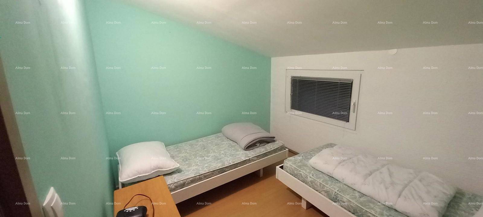 Schlafzimmer mit zwei Einzelbetten, mintgrüner Akzentwand und Dachschräge.