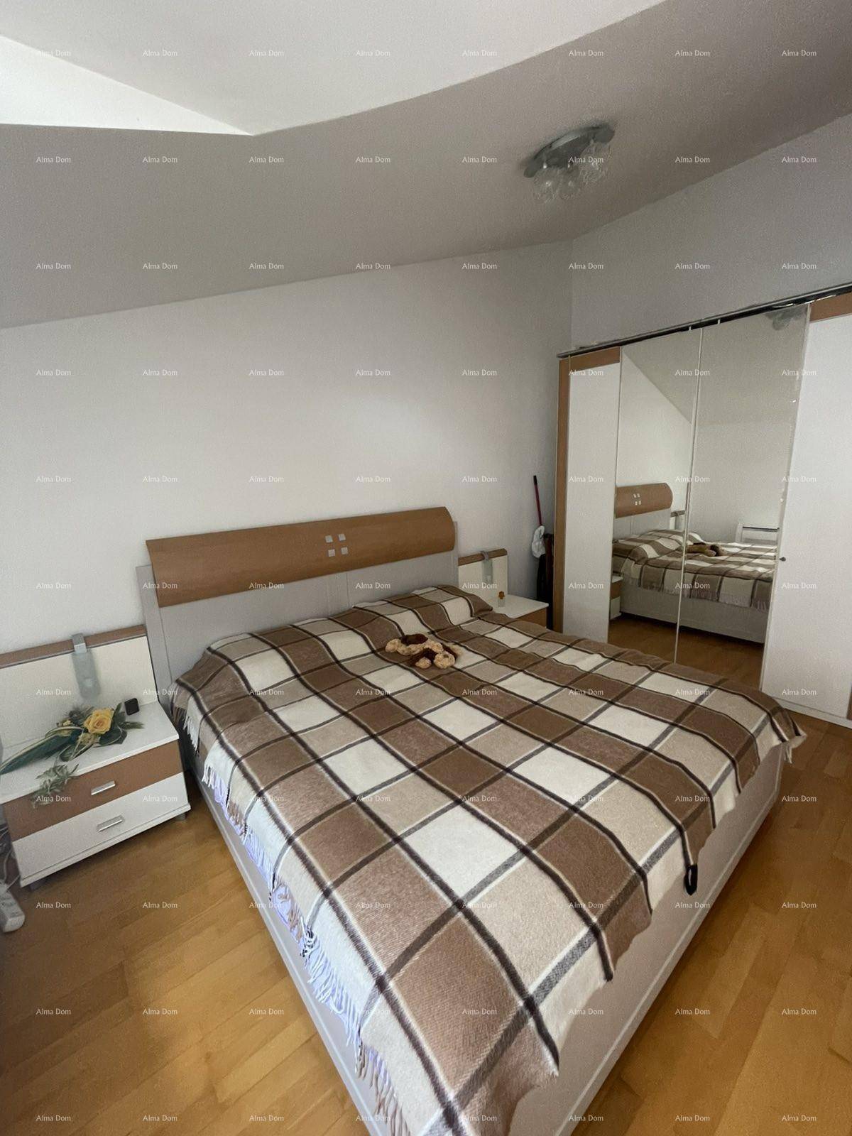 Helles Schlafzimmer mit Holzboden, großem Bett und Spiegelschränken.