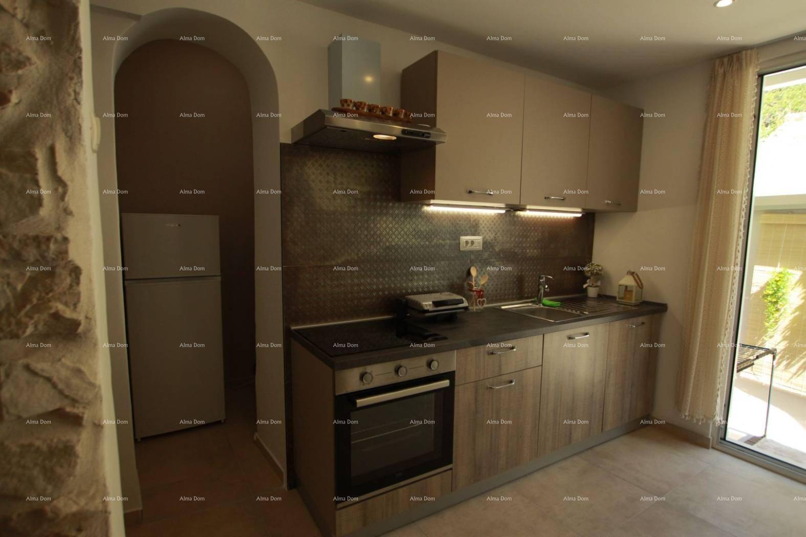 Funktionale Küche mit Holzoptik-Schränken, modernen Geräten und Zugang zum Außenbereich.