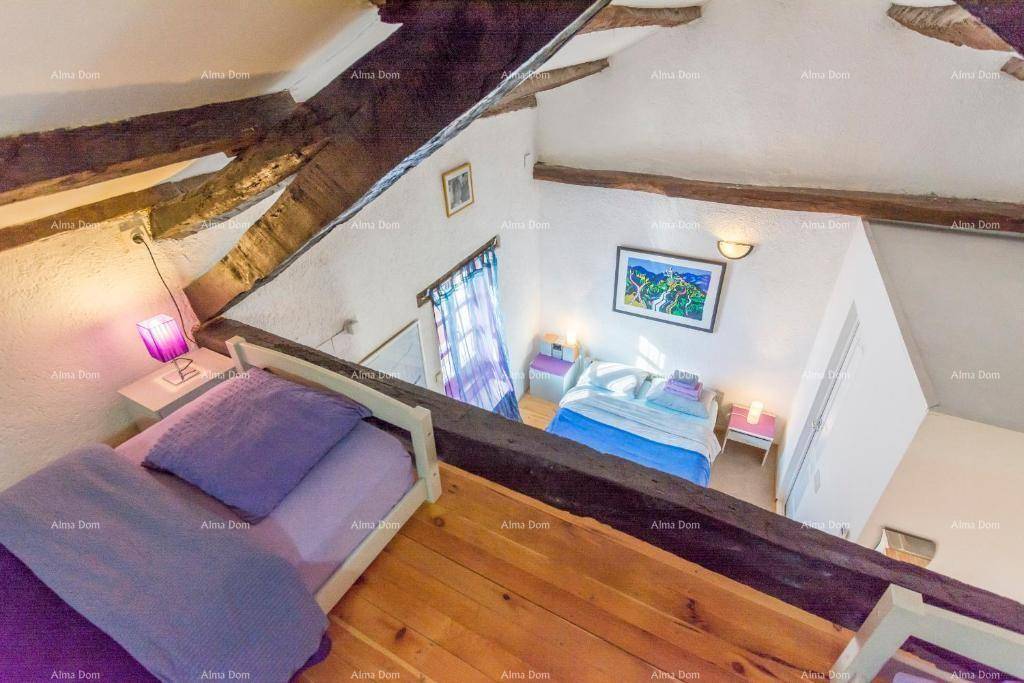 Blick vom oberen Schlafbereich auf den darunterliegenden Wohnraum mit Bett und Kunstwerk.