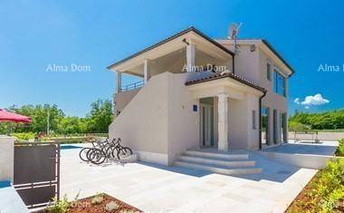 Seitenansicht der modernen Villa mit Eingangsbereich, Außentreppe und Fahrrädern im Vordergrund.