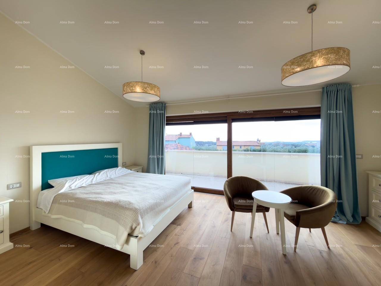 Schlafzimmer mit Doppelbett, Sitzgelegenheit und großen Fenstern mit Zugang zu einer Terrasse und Weitblick.