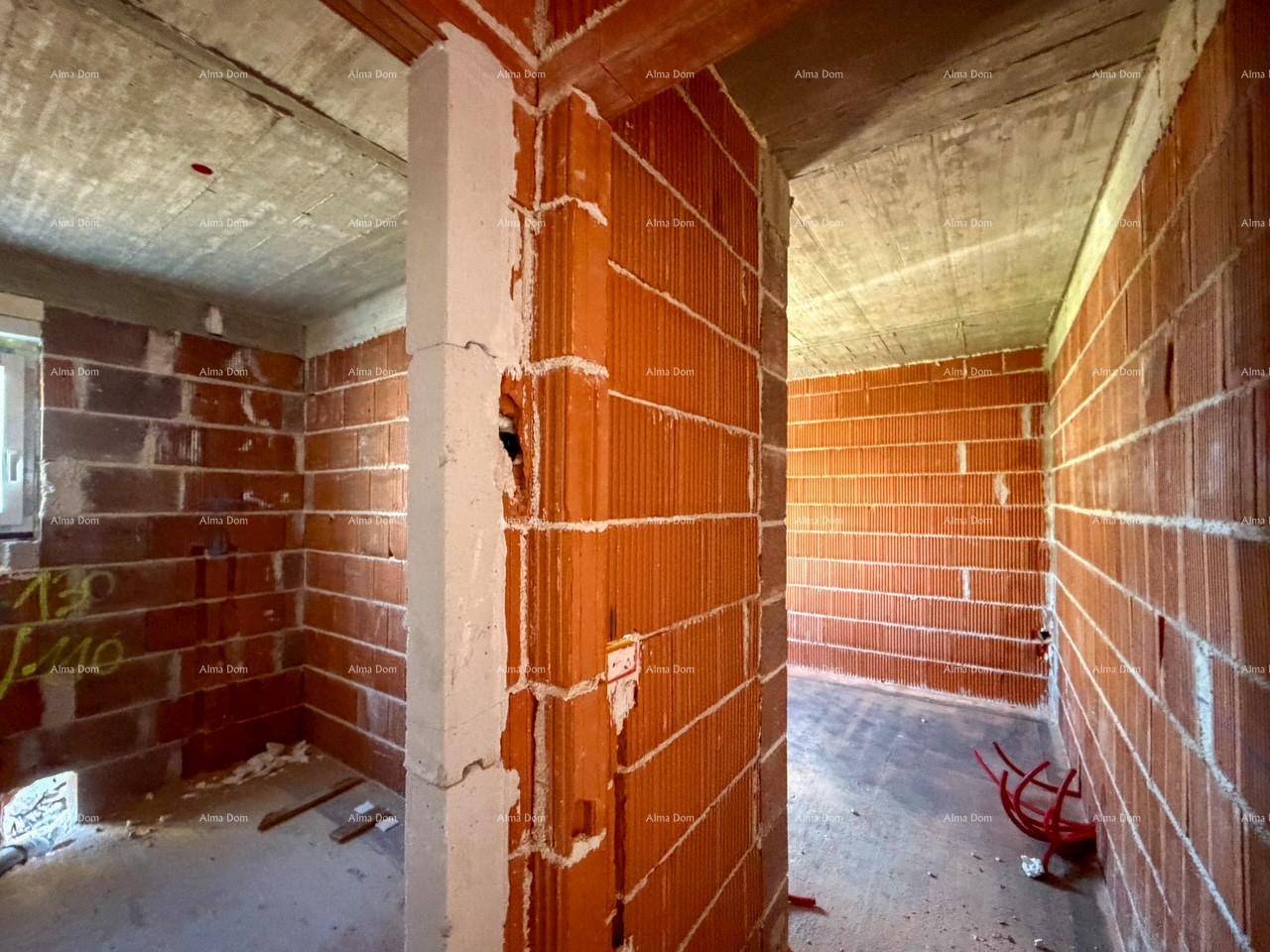 Flur im Rohbau mit Ziegelwänden und Blick in angrenzende Räume mit Betonboden.