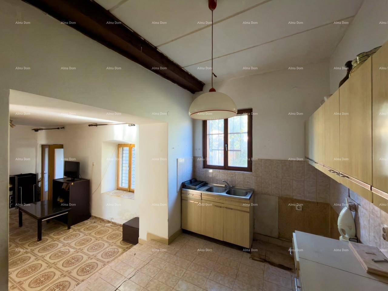Küche mit älteren Einbauschränken und Blick in den Wohnbereich, mit sichtbaren Deckenbalken.