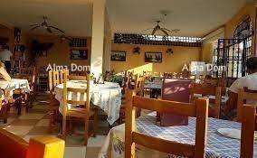 Heller Innenbereich des Restaurants mit Holztischen, Stühlen und Deckenventilatoren.