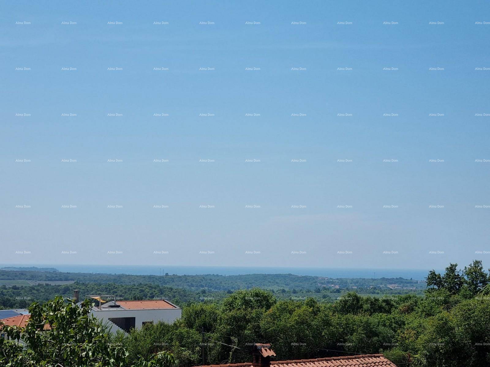 Panoramablick über die grüne Landschaft mit Häusern und dem fernen Meer unter strahlend blauem Himmel.
