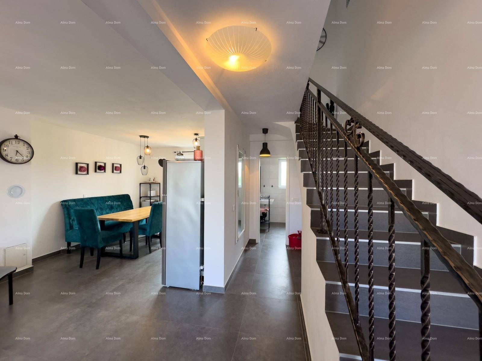 Offener Wohn- und Essbereich mit dunklen Fliesen und einer Treppe, die in die obere Etage führt.