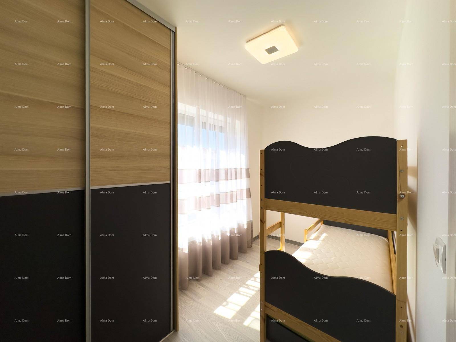 Kinderzimmer mit Etagenbett und großem Einbauschrank, hell durch das Fenster mit Vorhängen.