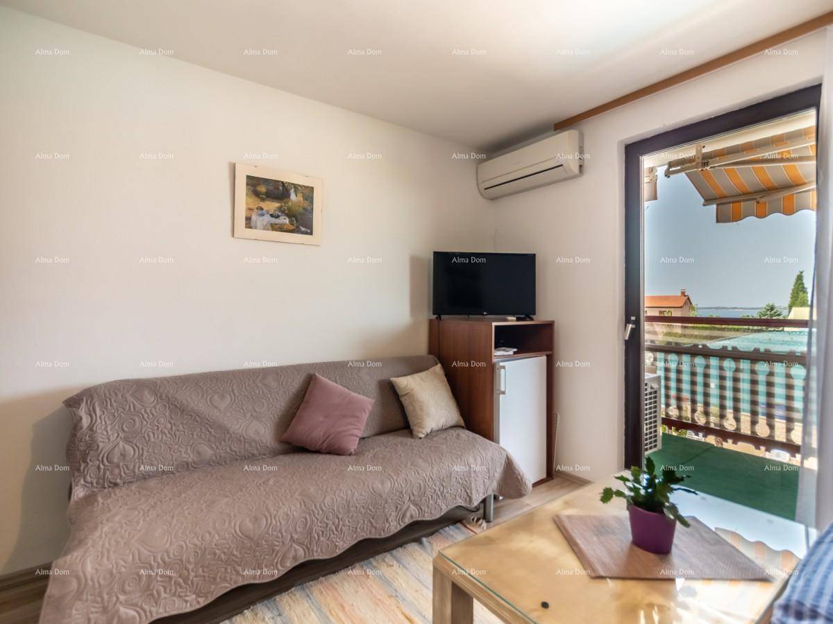 Wohnzimmer mit Sofa, Fernseher, Klimaanlage und Balkonzugang mit Meerblick.