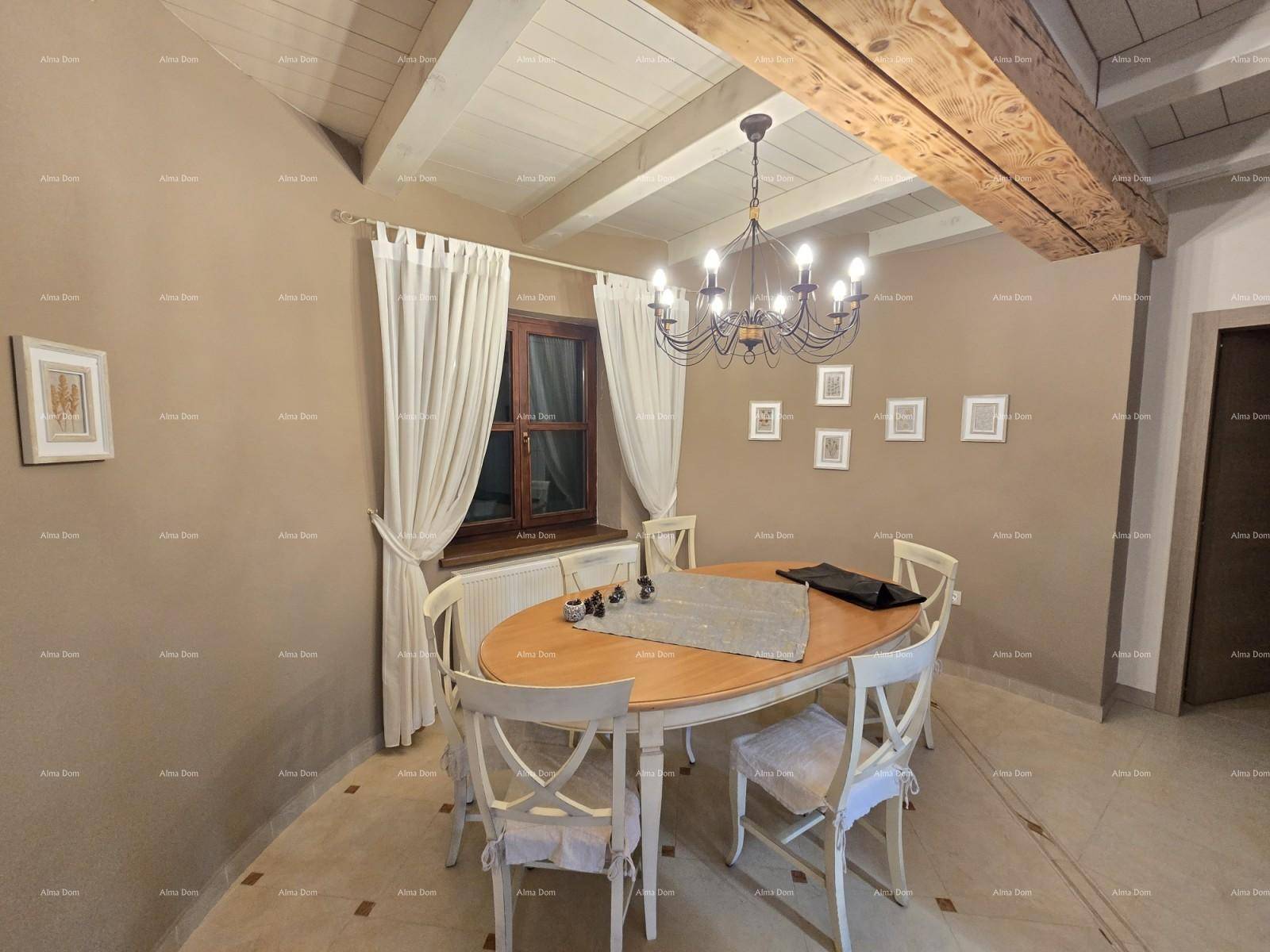 Esszimmer mit ovalem Holztisch, weißen Stühlen und einem Kronleuchter unter Holzbalkendecke.